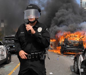 Los Angeles Police Department commander Cory Palka stands among several destroyed police cars as one explodes while on fire during a protest over the death of George Floyd, Saturday, May 30, 2020, in Los Angeles. (AP Photo/Mark J. Terrill)