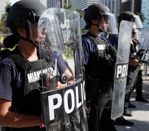 Police hold a line in front of Bayside Marketplace as protesters march, Sunday, May 31, 2020, in downtown Miami.