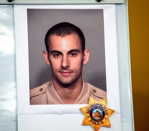 A photo of Las Vegas police officer Shay K. Mikalonis, 29, a four-year veteran of the department, is displayed during a media briefing at police headquarters in Las Vegas on Tuesday, June 2, 2020. (Steve Marcus/Las Vegas Sun via AP)
