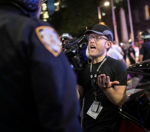 Associated Press videojournalist Robert Bumsted reminds a police officer that the press are considered “essential workers