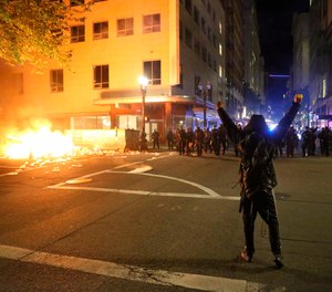 In this May 29, 2020, photo, a protester faces police officers in downtown in Portland, Ore. On May 30, the city's 911 system hit a 25-year record number of calls as civil unrest peaked over the killing of George Floyd.