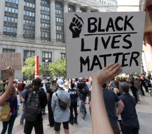 Protesters gather across the street from Chicago's City Hall, Wednesday, June 17, 2020. The Chicago Fire Department is investigating allegations that someone in a city fire truck removed a Black Lives Matter banner from a fence. (AP Photo/Charles Rex Arbogast)