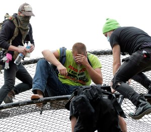 A street preacher, center, is tended to by volunteer medics after he was sprayed with a chemical irritant after he climbed a baseball backstop at Cal Anderson Park, Saturday, June 20, 2020, in the Capitol Hill Occupied Protest zone in Seattle.