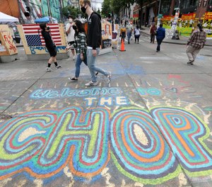 Pedestrians walk Sunday, June 21, 2020, in Seattle, where streets are blocked off in what has been named the Capitol Hill Occupied Protest (CHOP) zone.