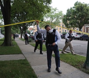 Police detectives canvas the area where a 3-year-old boy was fatally shot while riding in an SUV with his father on Saturday, June 20, 2020, in Chicago.