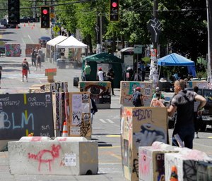 People walk amidst barricades in what has been named the Capitol Hill Occupied Protest zone in Seattle. (AP Photo/Ted S. Warren)