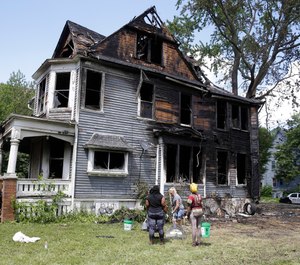 Workers clean up a duplex that was set on fire amid a police investigation scene Tuesday in Milwaukee. (Rick Wood/Milwaukee Journal-Sentinel via AP)