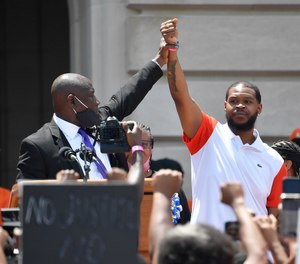 Attorney Benjamin Crump, left, holds up the hand of Kenneth Walker during a rally on the steps of the Kentucky State Capitol in Frankfort, Ky., Thursday, June 25, 2020.