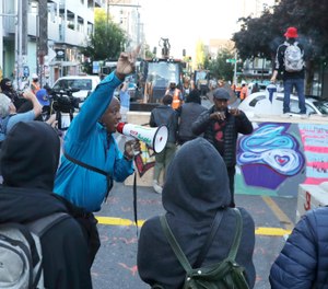 A man urges protesters not to be violent after workers and heavy equipment from the Seattle Department of Transportation arrived at the the CHOP (Capitol Hill Occupied Protest) zone in Seattle, Friday, June 26. (AP Photo/Ted S. Warren)