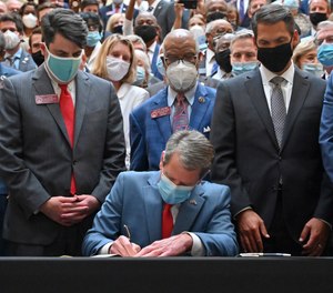 Gov. Brian Kemp, center, signs a bill into law on the last day of the legislative session at Georgia State Capitol, Friday, June 26, 2020.