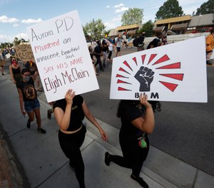 Protesters carry placards during a rally and march over the death of 23-year-old Elijah McClain, Saturday, June 27, 2020, outside the police department in Aurora, Colo. (AP Photo/David Zalubowski)