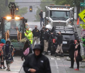 Seattle Police, at right, look on as Department of Transportation workers remove barricades at the intersection of 10th Ave. and Pine St. at the CHOP (Capitol Hill Occupied Protest) zone in Seattle. (AP Photo/Ted S. Warren)