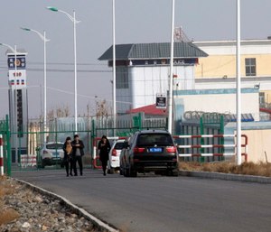 People walk by a police station by the front gate of the Artux City Vocational Skills Education Training Service Center in Artux in western China's Xinjiang region.