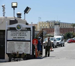 A Department of Corrections officer guards the main entryway leading into San Quentin State Prison in San Quentin, Calif. (AP Photo/Eric Risberg)