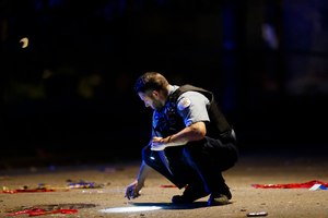 In this July 5, 2020, photo, an officer investigates the scene of a shooting in Chicago. Still reeling from the coronavirus pandemic and street protests over the police killing of Floyd, exhausted cities around the nation are facing yet another challenge: A surge in recent shootings has left dozens dead, including young children. Image: Armando L. Sanchez/Chicago Tribune via AP