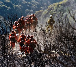 This Dec. 19, 2017 photo shows members of an inmate firefighting hand crew hiking on their way to work near Montecito, Calif. An inmate firefighter who was injured battling the Zogg Fire faces deportation to Laos due to his criminal convictions.