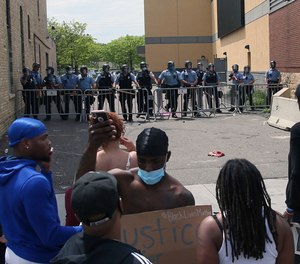 Minneapolis police stand guard against protesters at the Third Precinct on May 27, 2020, as people protest the death of George Floyd.