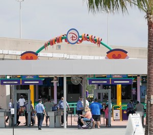 Guests enter the Magic Kingdom during the reopening at Walt Disney World, Saturday, July 11, 2020. Three Reedy Creek Fire Department paramedics, who serve Florida's Walt Disney World theme parks and resorts, say they have been denied workers' compensation after contracting COVID-19.