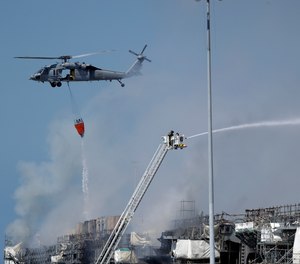 A helicopter drops water on the USS Bonhomme Richard as crews fight the fire Monday, July 13, 2020, in San Diego. The fire and an explosion on the ship have injured at least 59 people, including 36 sailors.