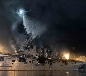 A helicopter from Helicopter Sea Combat Squadron (HSC) 3 combats a fire aboard the amphibious assault ship USS Bonhomme Richard (LHD 6) at Naval Base San Diego.
