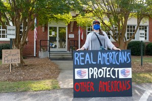A protester holds up a sign for a mask mandate in schools during the