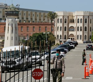 In this July 9, 2020, file photo, a correctional officer closes the main gate at San Quentin State Prison in San Quentin, Calif.