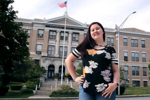 Kayleigh Bergh, of Haverhill, Mass., poses at city hall, Thursday, July 16, 2020, across the street from the polling station where she will be working on Election Day, in Haverhill. State and local election officials across the country are trying to recruit younger workers to staff polling places on Election Day in November. Image: AP Photo/Charles Krupa