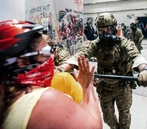 A federal officer pushes back demonstrators at the Mark O. Hatfield United States Courthouse on Tuesday, July 21, 2020, in Portland, Ore.