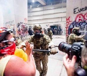 A federal officer pushes back demonstrators at the Mark O. Hatfield United States Courthouse on Tuesday, July 21, 2020, in Portland, Ore.