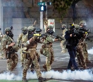 In this July 20, 2020 file photo Federal agents use crowd control munitions to disperse protesters at the Mark O. Hatfield United States Courthouse in Portland, Ore.