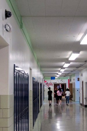 In this July 10, 2018 photo, students walk down a hallway at Lockport High School in Lockport, N.Y., as a camera with facial recognition capabilities, upper left, hangs on the wall waiting for its installation to be completed. Image: AP Photo/Carolyn Thompson