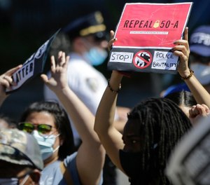 In this June 8, 2020 file photo, a protester in Queens holds a sign calling for the repeal of section 50-a, a law prohibiting the public release of firefighter, police officer and corrections officer disciplinary records. (AP Photo/Frank Franklin II, File)