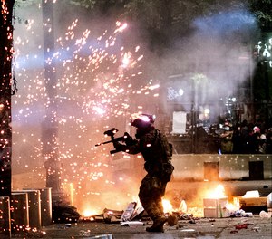 A federal officer fires crowd control munitions at protesters on Friday, July 24, 2020, in Portland, Ore.