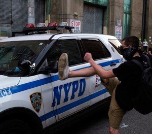 A protester kicks a police vehicle in an attempt to break its side mirror during a protest Saturday, July 25, 2020, in New York.