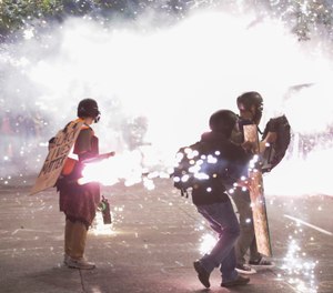 Protesters walk away from crowd control munitions launched by federal officers during a Black Lives Matter protest at the Mark O. Hatfield United States Courthouse Sunday, July 26, 2020, in Portland, Ore. (AP Photo/Marcio Jose Sanchez)