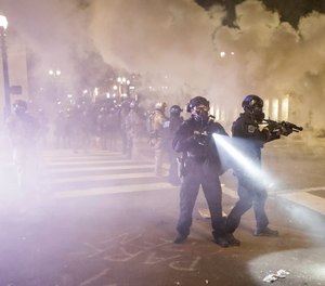 Federal officers deploy tear gas and crowd control munitions at a protest at the Mark O. Hatfield United States Courthouse Tuesday, July 28, 2020, in Portland, Ore. (AP Photo/Marcio Jose Sanchez)
