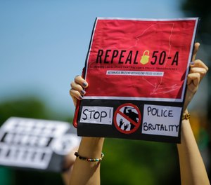 A protester holds a sign June 8, 2020 in Queens, calling for the repeal of section 50-a, a law prohibiting the public release of police officer disciplinary records. (AP Photo/Frank Franklin II, File)