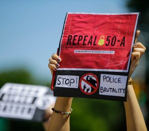 A protester holds a sign outside Queens County Criminal Court in June, calling for the repeal of section 50-a, a law prohibiting the public release of police officer and firefighter disciplinary records. State lawmakers approved the repeal earlier this year, and a judge has now rejected Buffalo fire and police unions' bids to have some records excluded from the release.