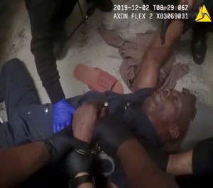 In this image made from video and released by the Forsyth County (N.C). Jail, authorities restrain John Neville in his cell as a nurse speaks with him. (Photo/Forsyth County Jail via AP)