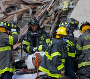 Baltimore City Fire Department carries a person out from the debris after an explosion in Baltimore on Monday, Aug. 10, 2020. Baltimore firefighters say an explosion has levelled several homes in the city. (AP Photo/Julio Cortez)