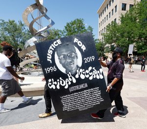 Demonstrators carry a placard during a rally and march over the death of Elijah McClain outside the police department in Aurora, Colo. The parents of McClain have filed a federal lawsuit against the officers who stopped McClain and the paramedics who administered ketamine during the stop.