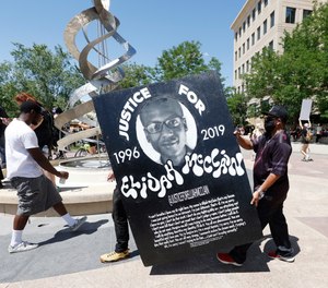 In this June 27, 2020, file photo, demonstrators carry a giant placard during a rally over the death of Elijah McClain outside the police department in Aurora, Colo.