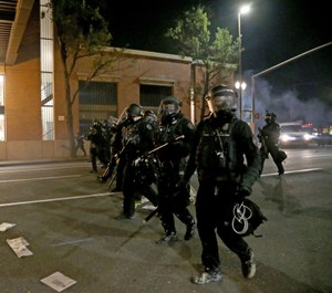 Portland police declare a riot at the Multnomah County Building, on Tuesday, Aug. 18, 2020, in Portland, Ore. (Beth Nakamura/The Oregonian via AP)
