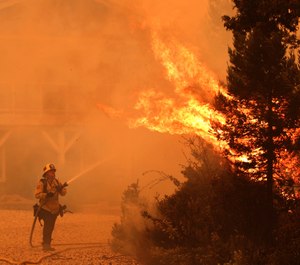 A firefighter directs water onto a tree that exploded in flames outside a house northwest of Santa Cruz, Calif. About 22,000 people in Santa Cruz and San Mateo County have self-evacuated, fleeing their homes to escape dozens of wildfires. (Photo/Shmuel Thaler, The Santa Cruz Sentinel via AP)