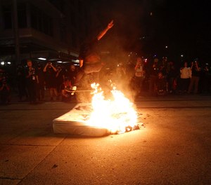 A protester jumps over a fire on his skateboard on Wednesday, Aug. 19, 2020. (Sean Meagher/The Oregonian via AP)