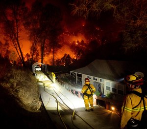 Firefighters protect a home in the Berryessa Estates neighborhood of unincorporated Napa County, Calif., as the LNU Lightning Complex fires burn on Friday, Aug. 21, 2020.