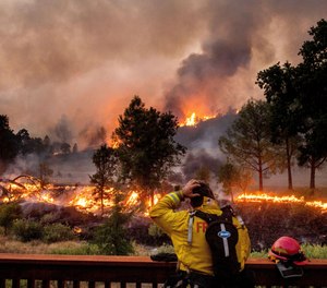 In this Aug. 21, 2020, file photo, a firefighter rubs his head while watching the LNU Lightning Complex fires spread through the Berryessa Estates neighborhood of unincorporated Napa County, Calif. Deadly wildfires in California have burned more than 4 million acres (6,250 square miles) this year — more than double the previous record for the most land burned in a single year in the state.
