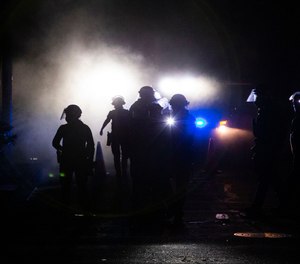 A march on the Portland police union headquarters drew a rapid police response after someone set a fire next to the building.Monday, Aug. 24, 2020. (Beth Nakamura/The Oregonian via AP)