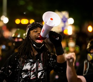 A protester uses a megaphone during a demonstration in Portland, Ore., on Tuesday, Aug. 25, 2020. (Dave Killen/The Oregonian via AP)