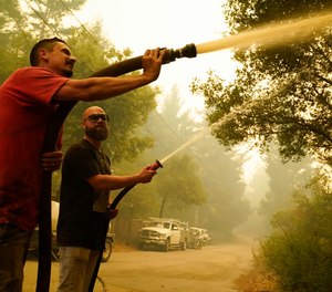 Two civilians attempt to fight the CZU Lightning Complex Fire in Bonny Doon, Calif. Some California residents have returned to evacuation zones trying to defend homes from wildfires. Fire officials warn that this could hamper official firefighting efforts.